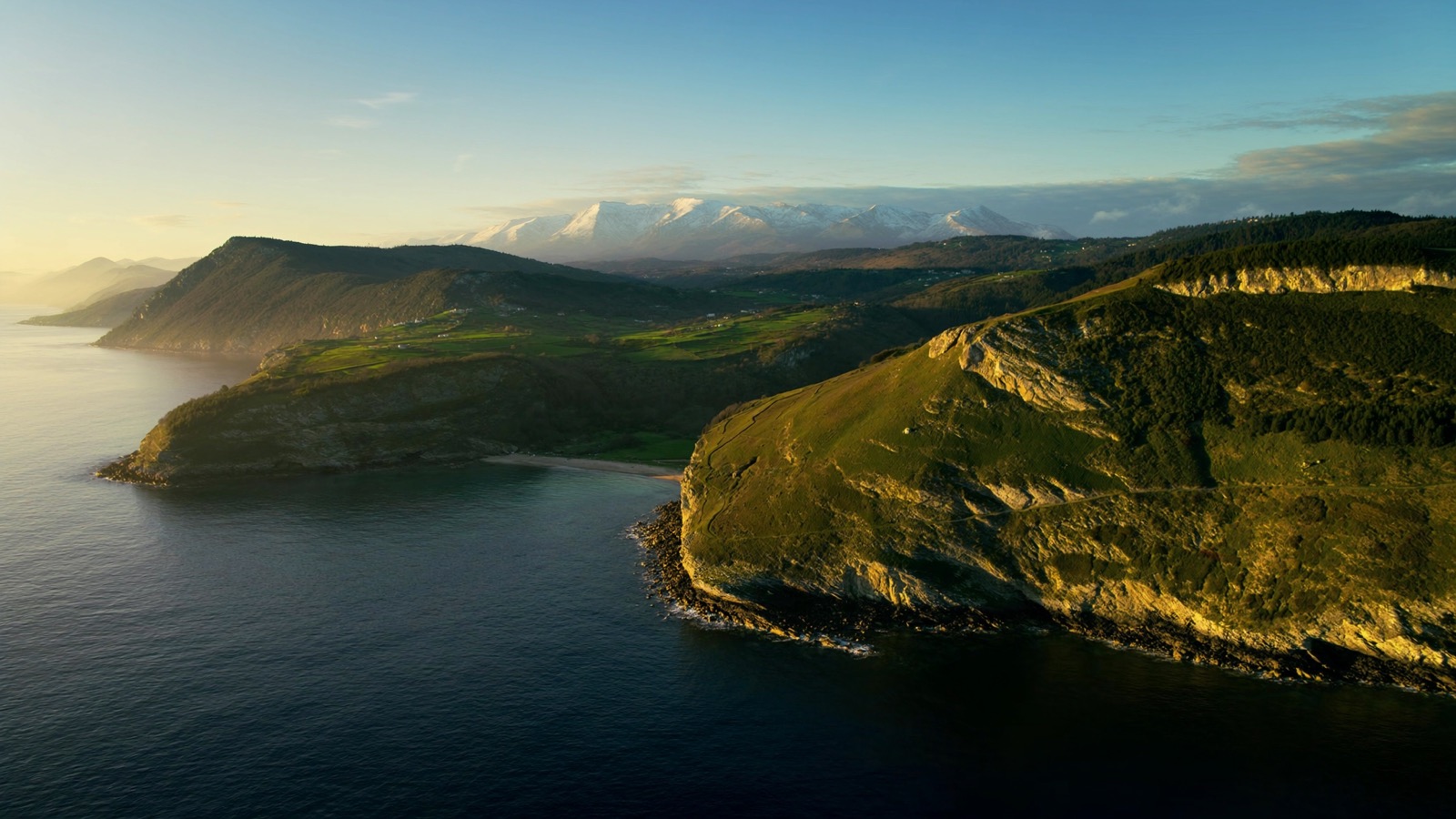 Costa verde de Asturias con acantilados y los Picos de Europa al fondo
