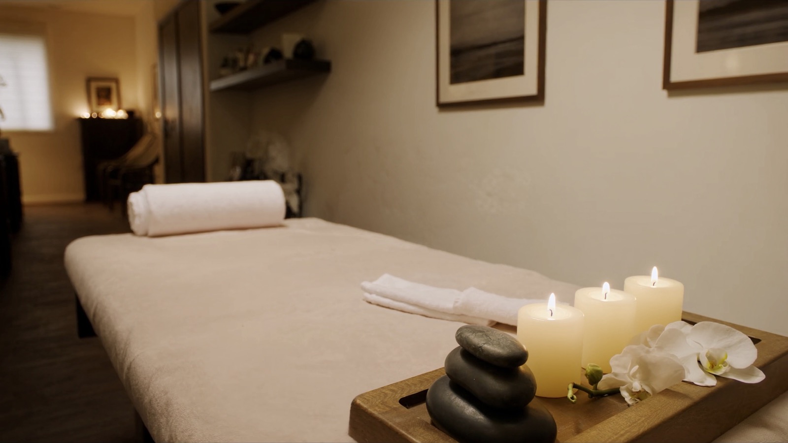 Sala de spa con camilla de masaje, toallas y velas